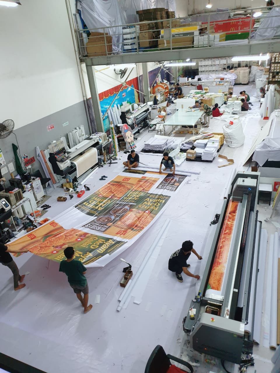 Production floor with wide-format printers and a large McDonald's banner in progress